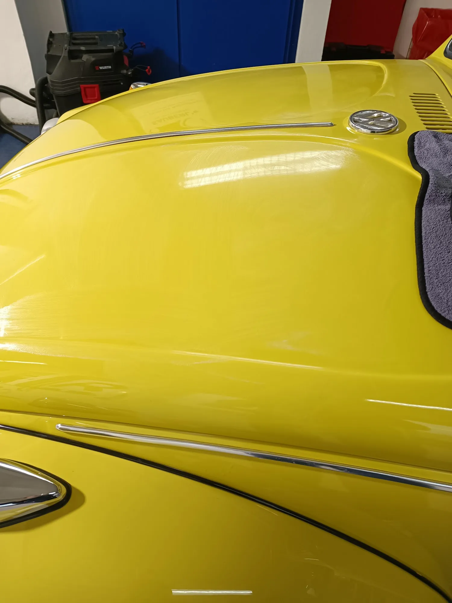 Motorhaube eines gelben VW Käfers mit Hochglanzreflexionen