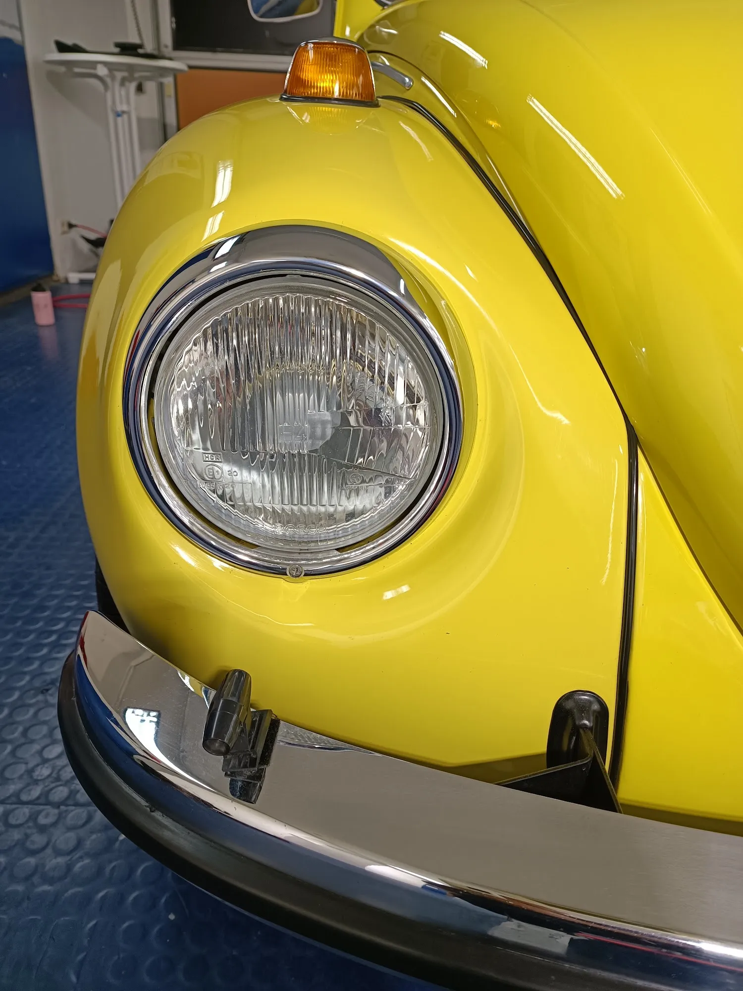 Chromstoßstange und Scheinwerfer eines restaurierten gelben VW Käfer