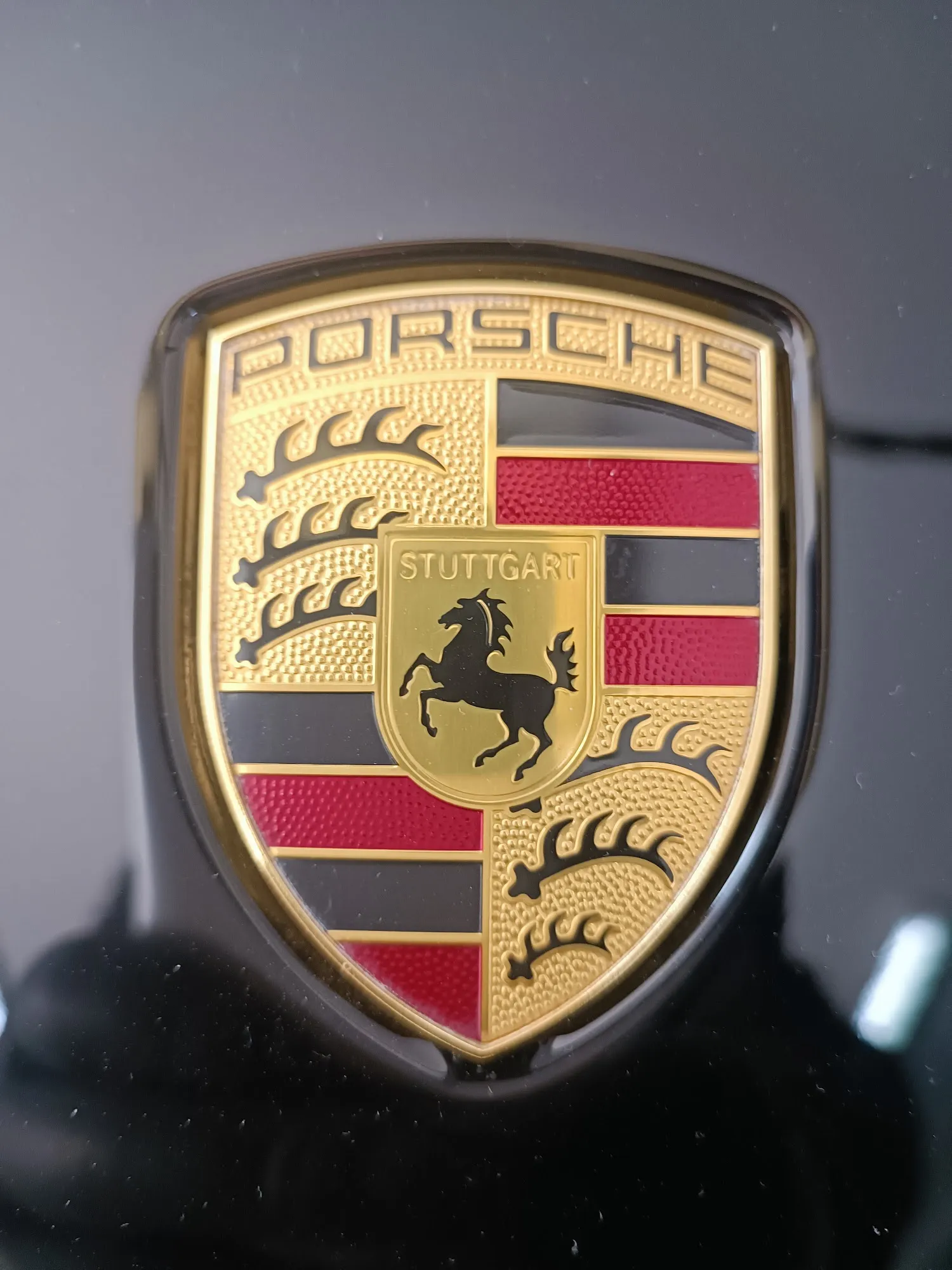 Detailaufnahme des Porsche Wappens auf hochglänzendem Lack